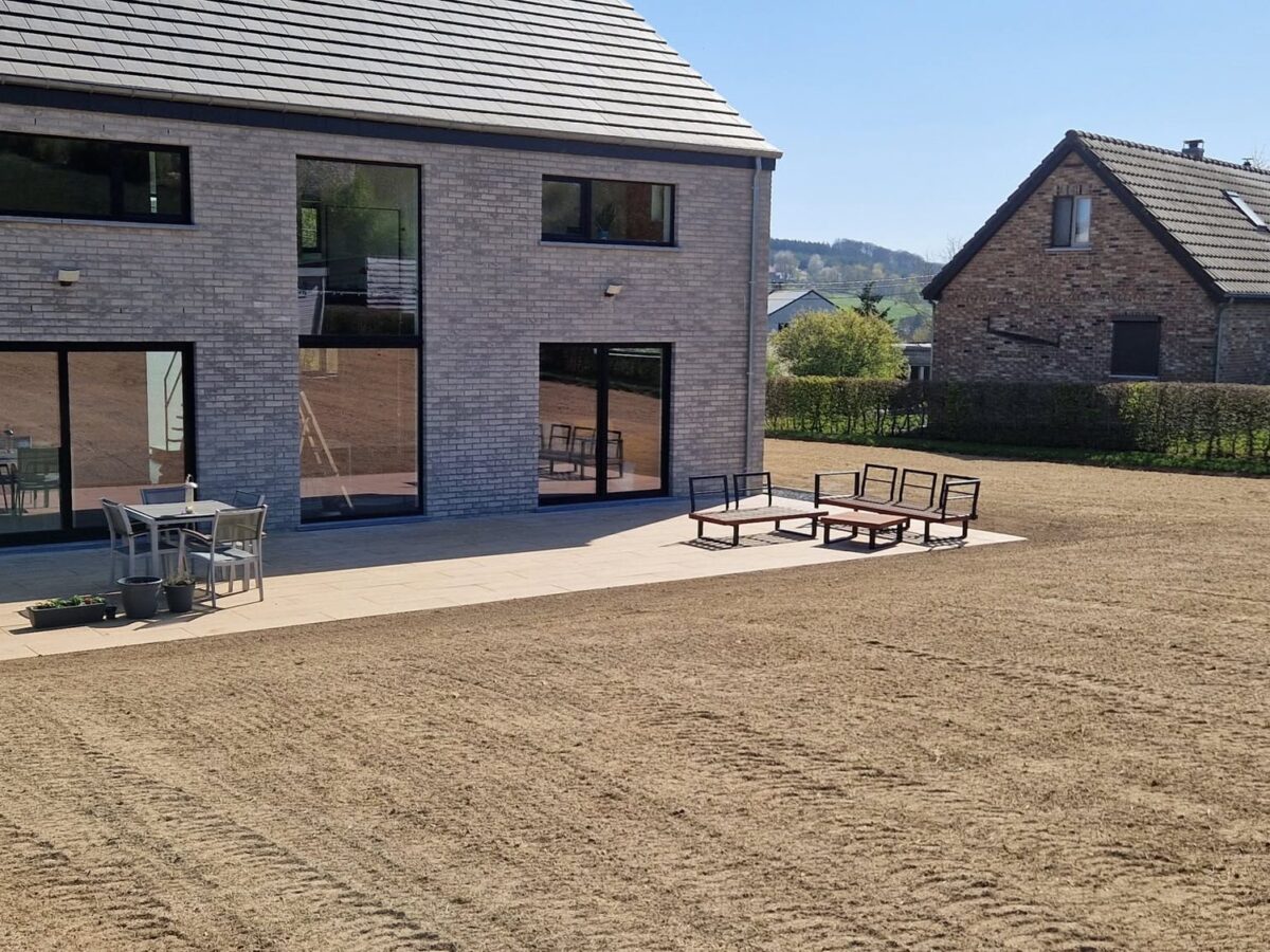 Terrain de construction remis à niveau : terrasse céramique et surface préparée pour le semis