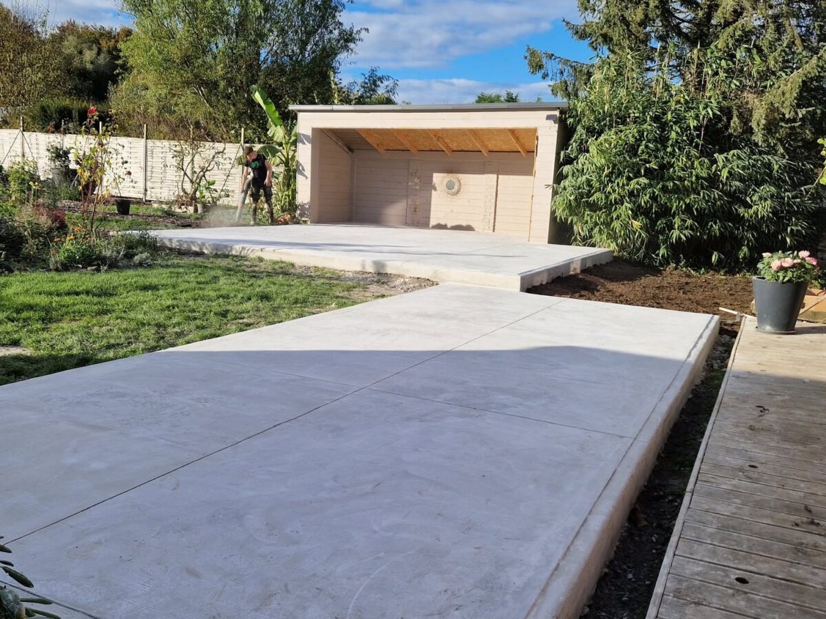 Dalle béton lissée reliant le jardin à un abri ouvert