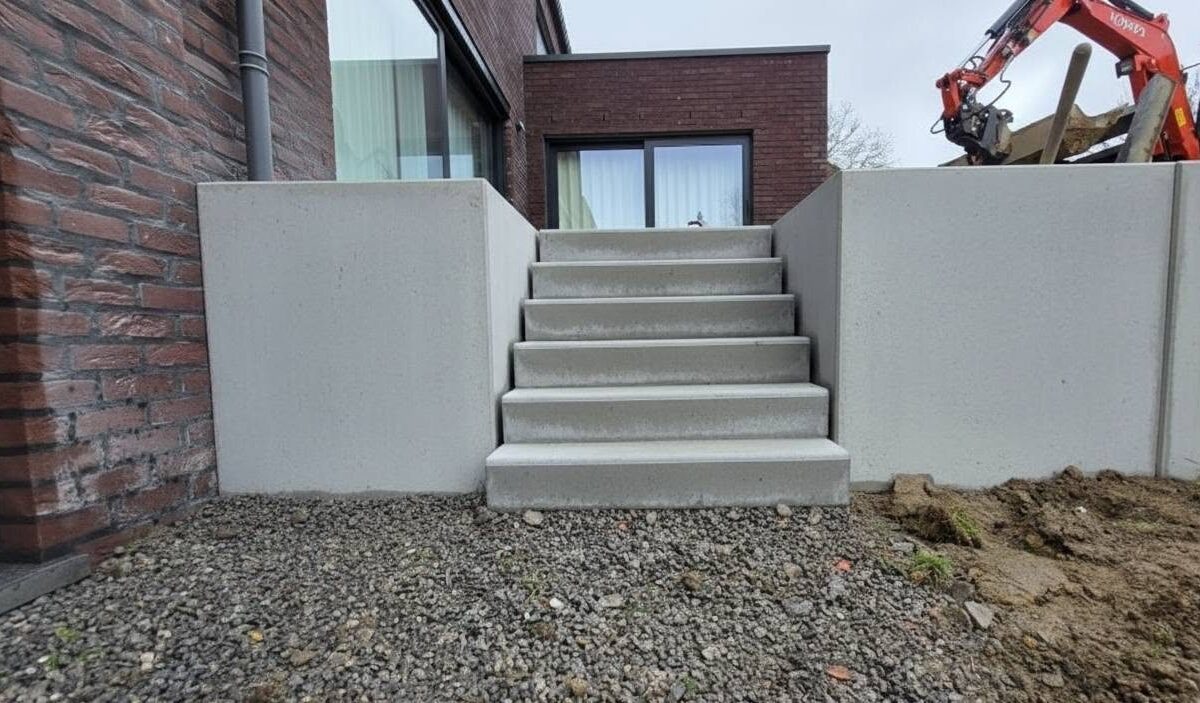 Murs de soutènement en éléments préfabriqués en L et escalier béton contre une façade