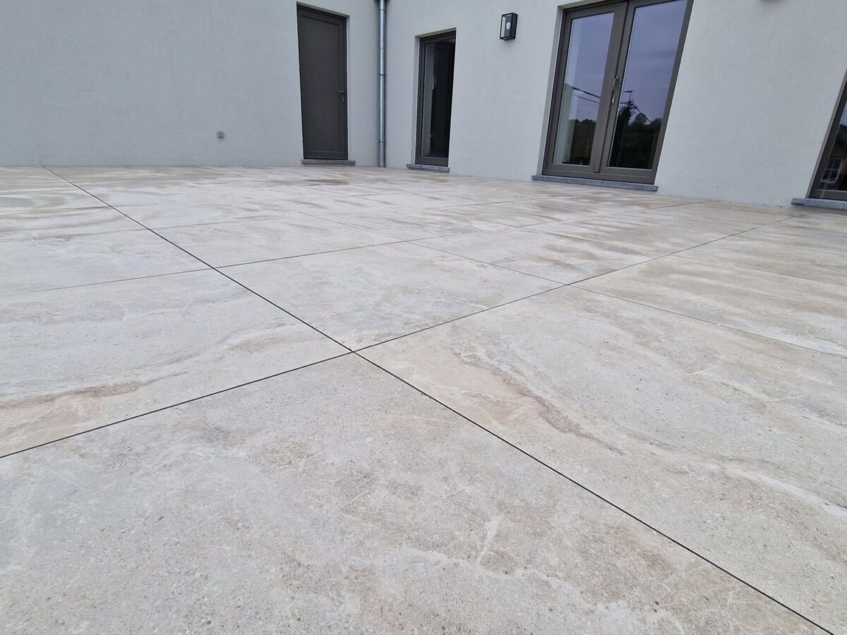 Terrasse en dalles céramiques 90 × 90 claires au pied d'une maison contemporaine blanche